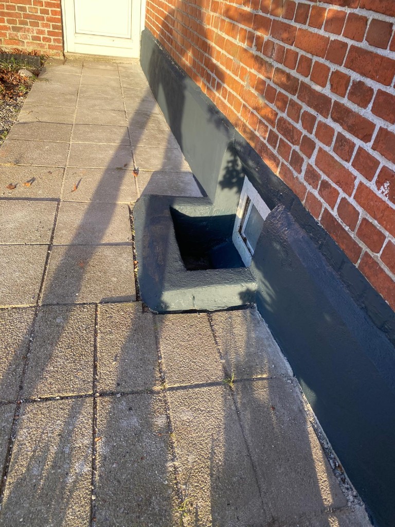 Nypudset sokkel på teglfacade — mørkegrå sokkelpuds